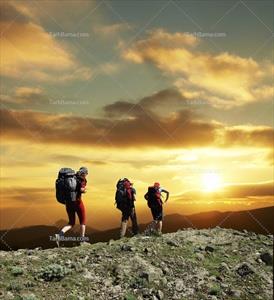تصویر با کیفیت سه کوهنورد روی قله در غروب آفتاب